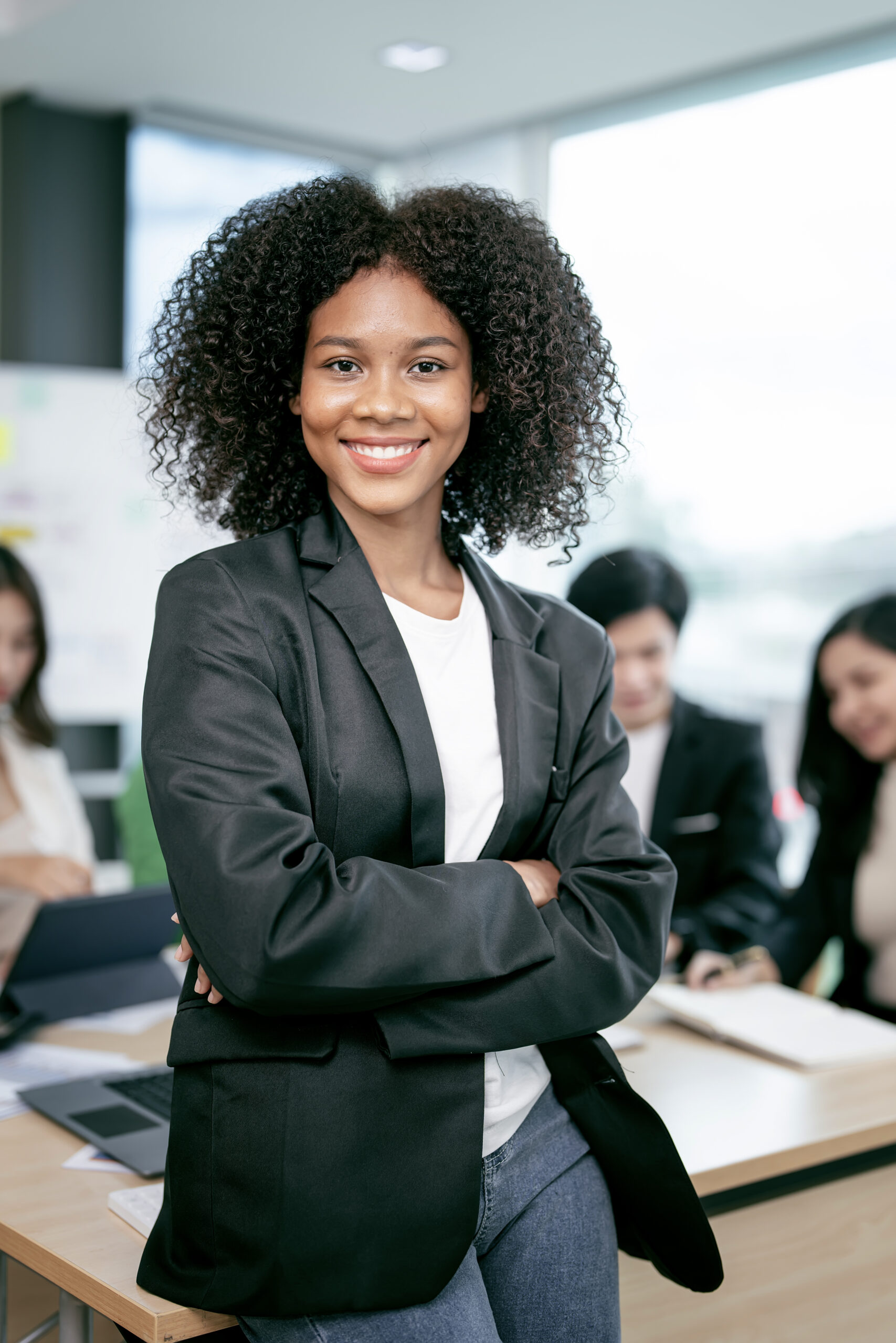 Successful businesswoman standing in creative office and smiling to camera. Portrait of beautiful african woman standing in front of business team at office.